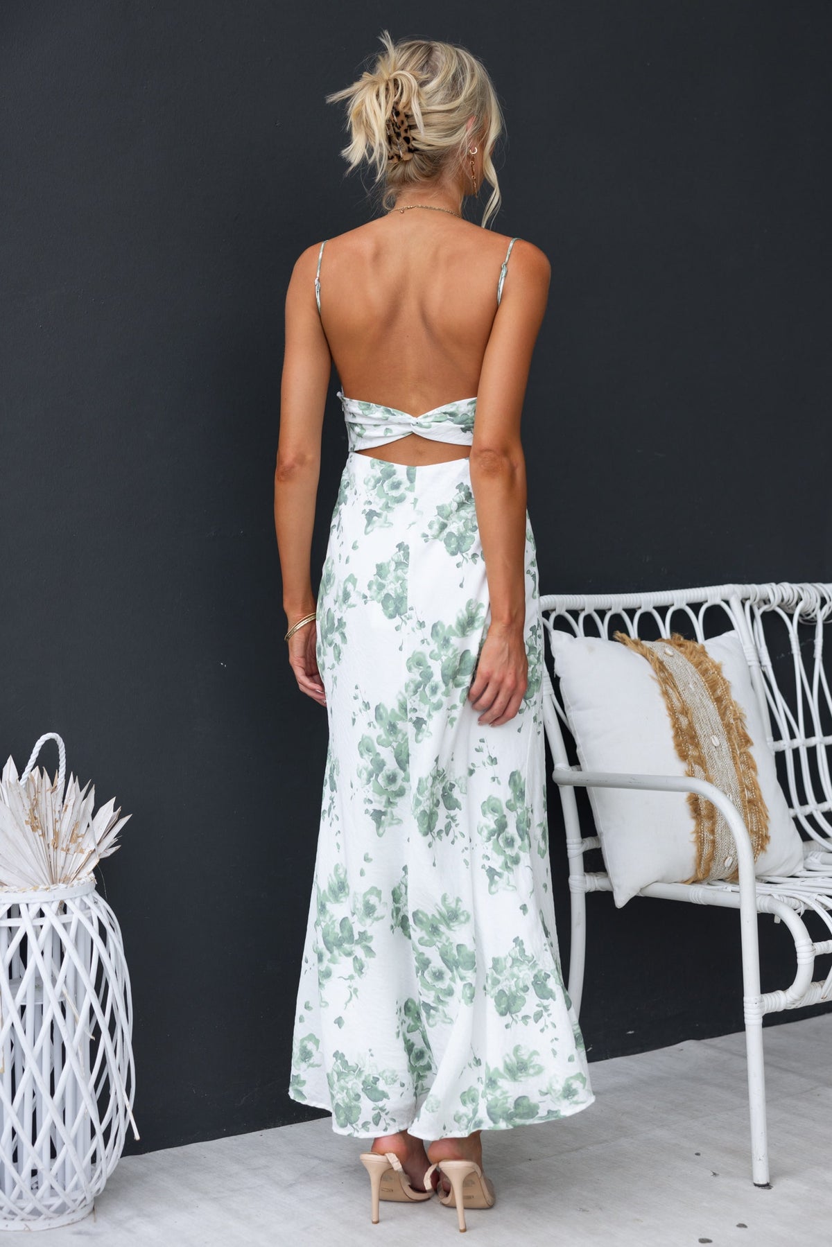 Back view of a woman in a floral print Freyda maxi dress with adjustable straps and cut-out detail.