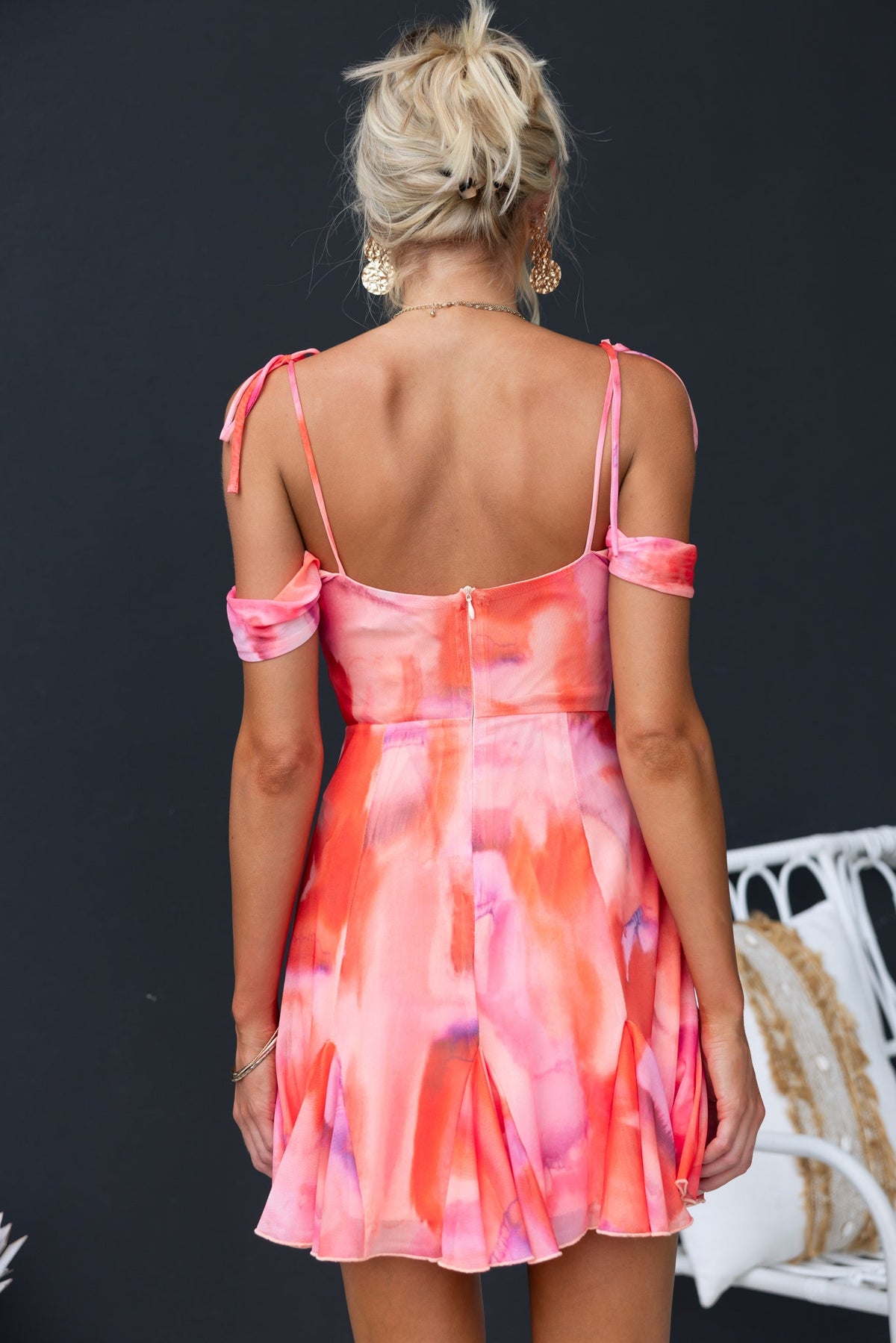 Back view of the Rhya Dress featuring adjustable tie straps and a vibrant pink and orange watercolor design.