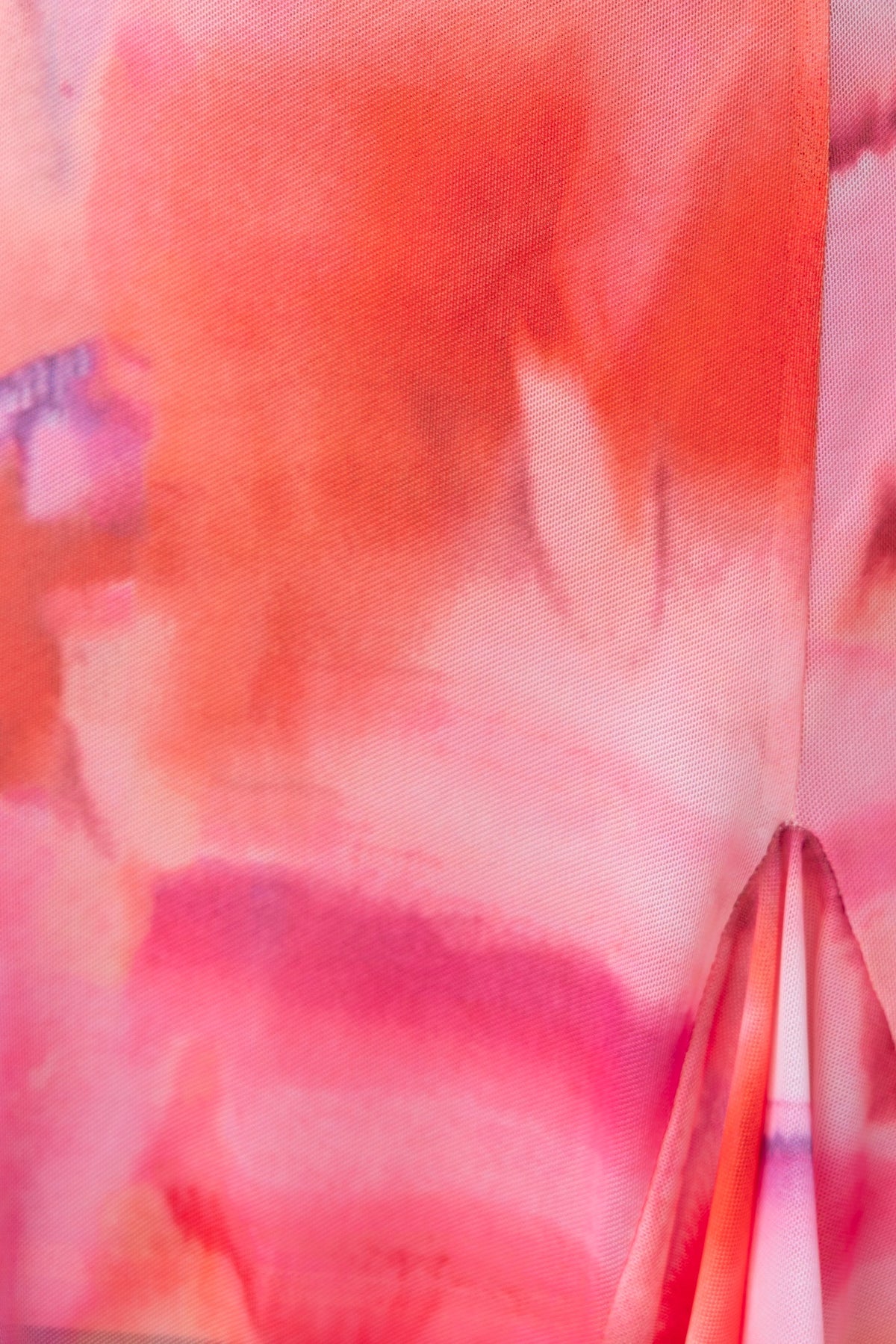 Close-up of vibrant orange and pink watercolor fabric pattern on Rhya Dress, showcasing its mesh texture.