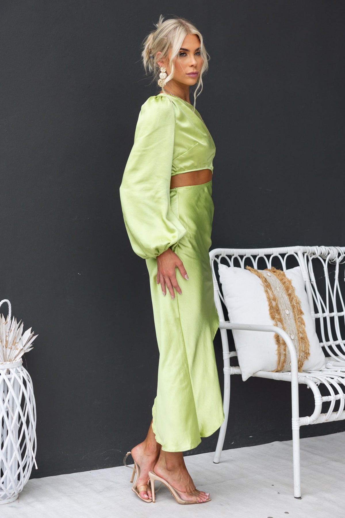 Jeyne Midi Dress in vibrant green, featuring a one-shoulder design and asymmetric hem, styled with clear heels.