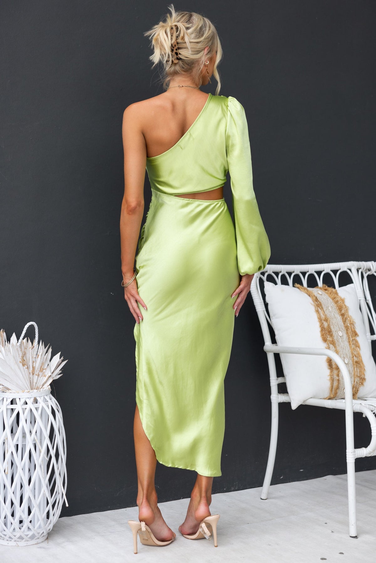 Model showcasing the Jeyne Midi Dress in lime green, featuring an asymmetrical hem and one-shoulder design.
