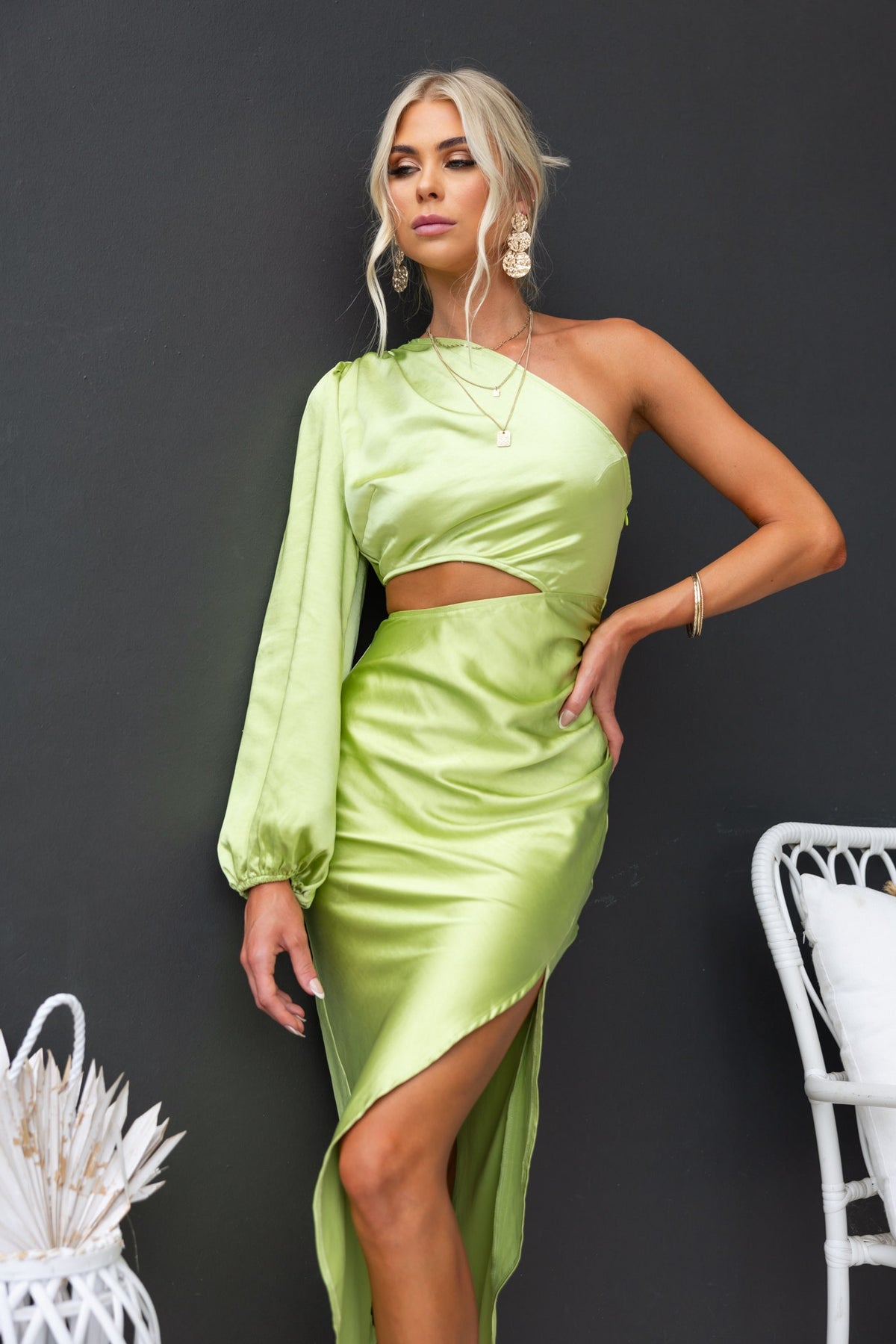 Model showcasing the Jeyne Midi Dress in lime green, featuring one-shoulder design and cut-out waist.