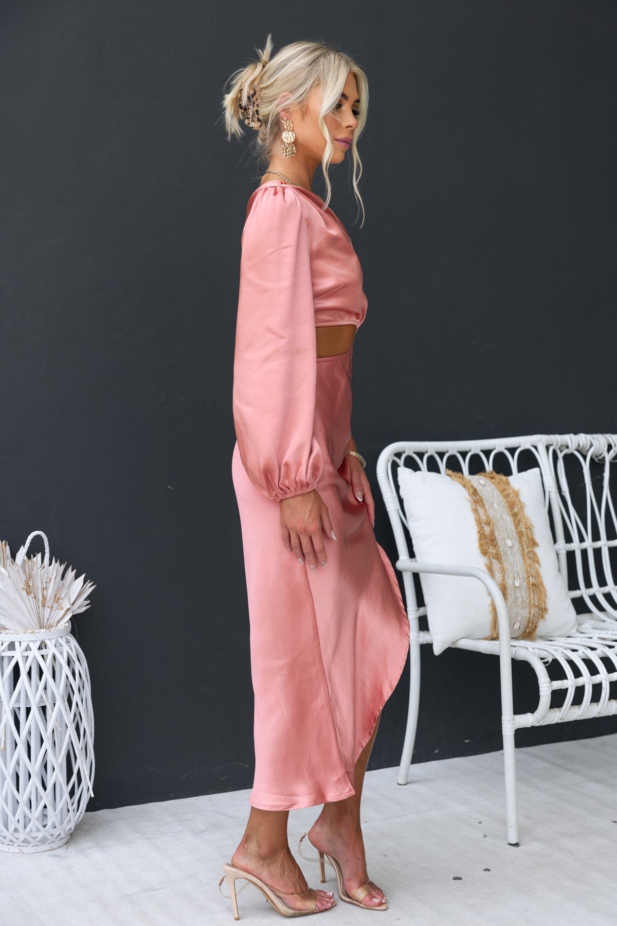 Model wearing a Jeyne Midi Dress in satin pink, featuring a one-shoulder design, cut-out waist, and asymmetric hem.