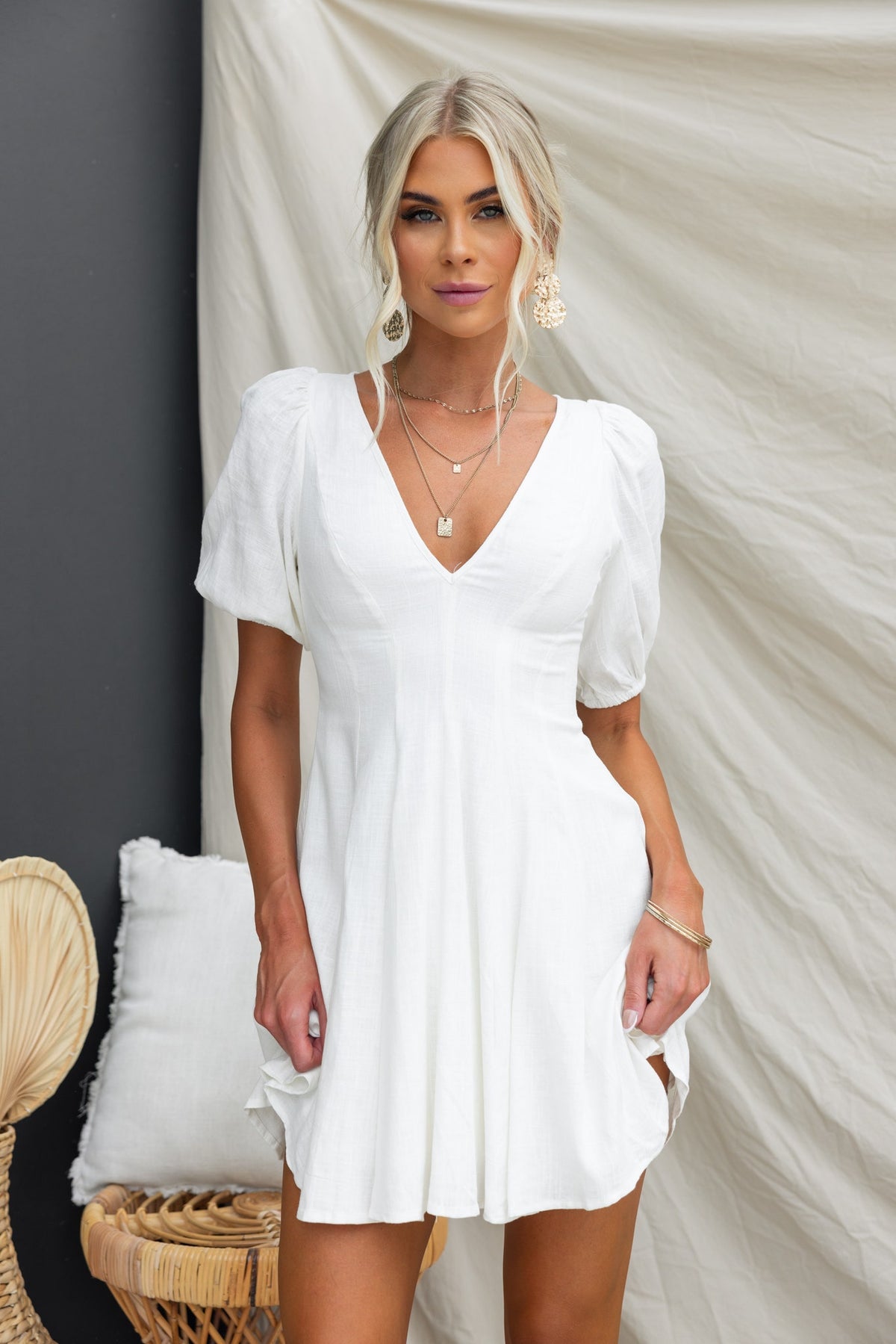 Model wearing a V-neck Morado Dress with puff sleeves, featuring a linen look and a flattering fit in a stylish setting.