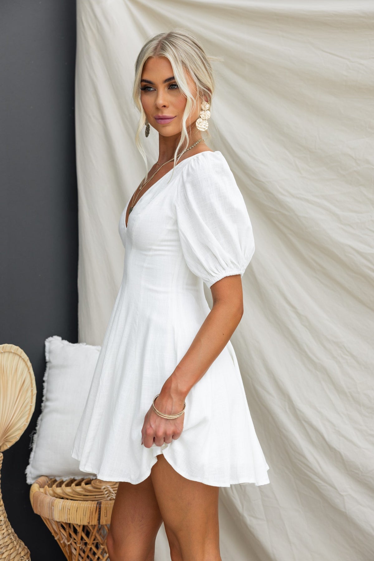 Model wearing a white V-neck dress with puff sleeves, showcasing a flattering fit and stylish design.