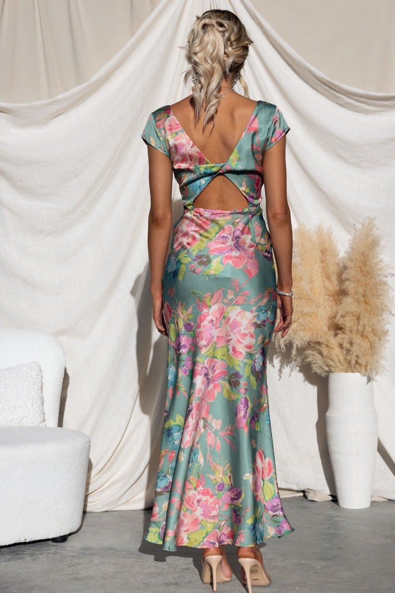 Back view of a floral print maxi dress with cap sleeves and a twist detail at the back, showcasing a stylish cut-out design.