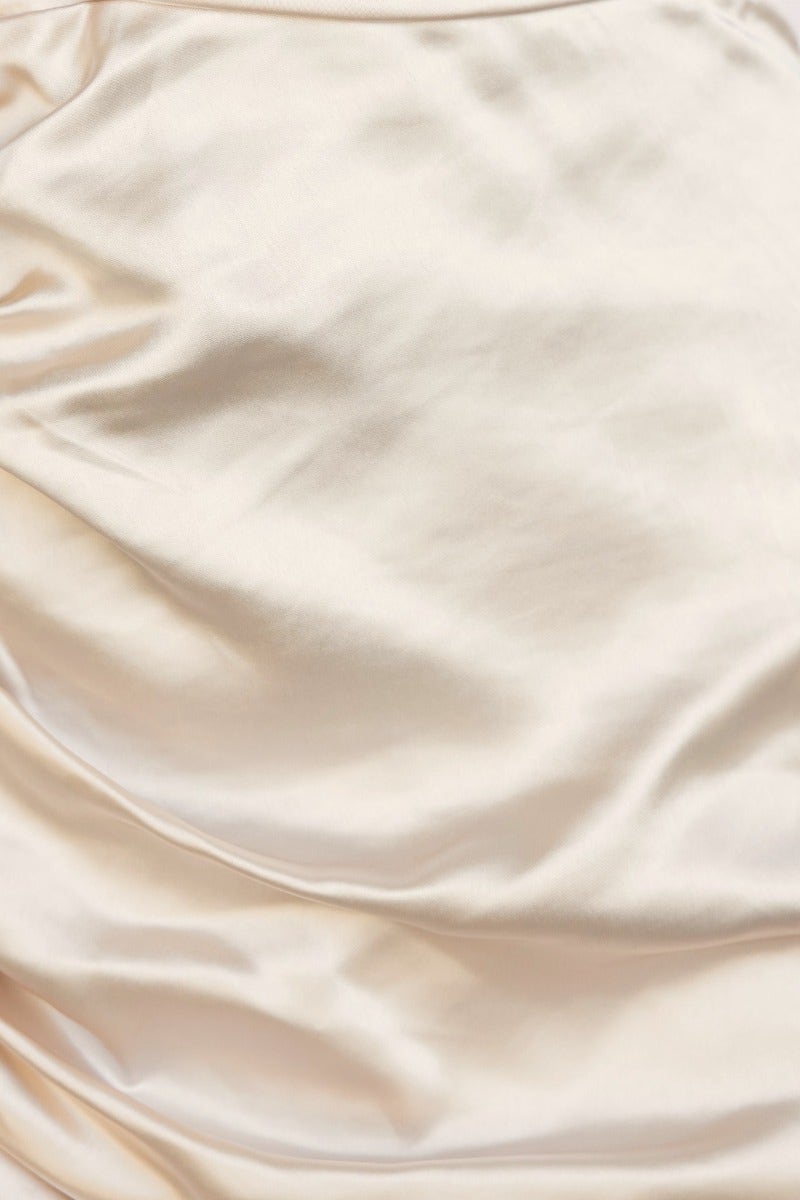Close-up of satin fabric showcasing a smooth, elegant texture in creamy beige for the On The Way Midi Dress.