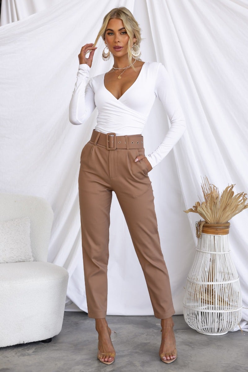 Model wearing Kaniva Pants with removable belt, front pockets, and slim fit in a stylish setting.