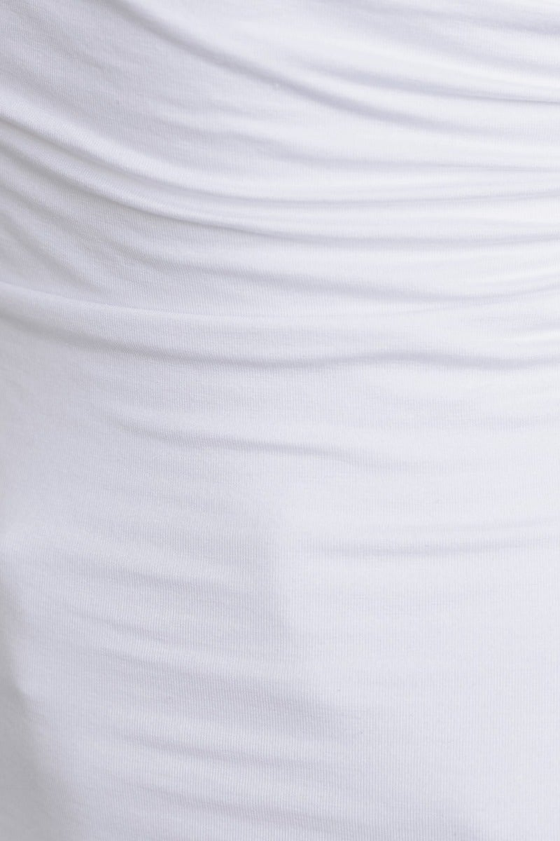Close-up of white fabric featuring soft ruching details, highlighting texture and stretch of the material in a top.