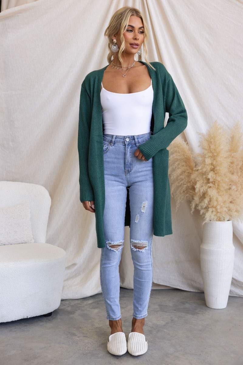 Motherly Cardigan in green, featuring ribbed knit, longline fit, and front pockets, styled with ripped light jeans.