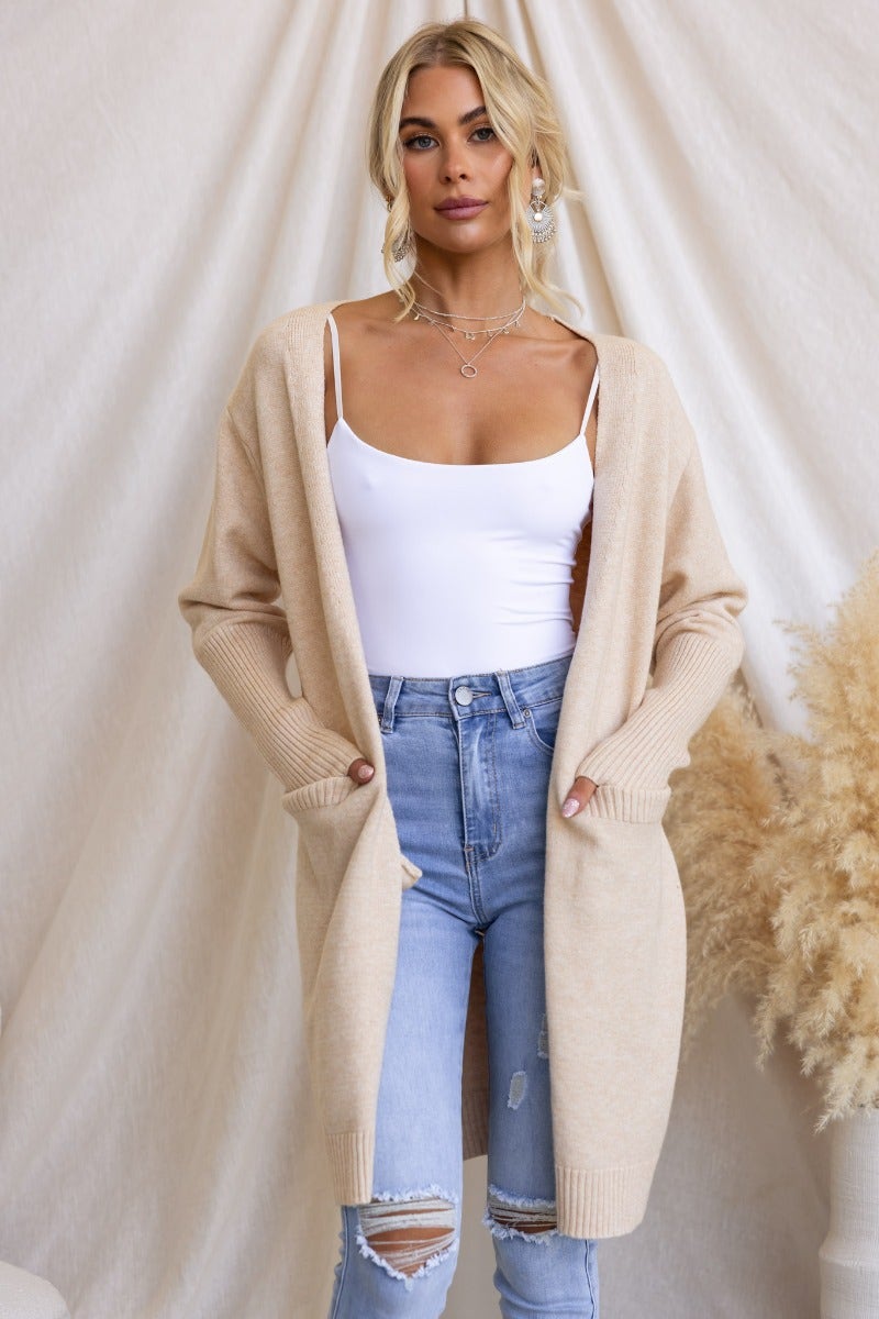 Tan Motherly Cardigan worn by model with front pockets, featuring longline fit and ribbed knit fabric.