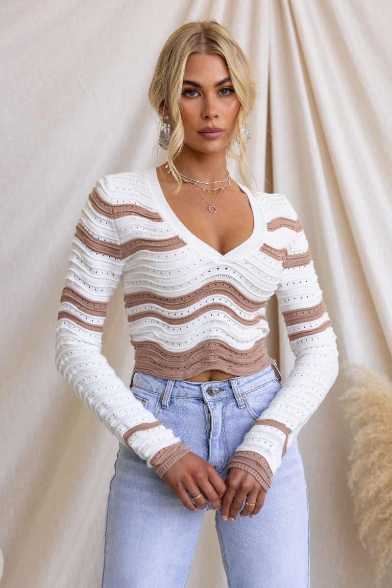 Alanis Top with scoop neckline in white and beige, featuring semi open weave and stylish fit, worn with high-waisted jeans.
