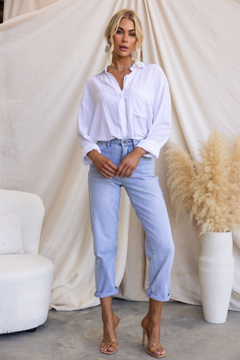 Model wearing Isoka Jeans, mid-high waist denim jeans with a relaxed fit, styled with a white button-up shirt.