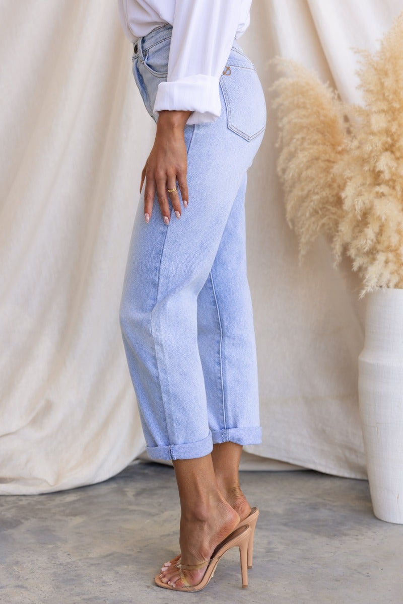 Side view of Isoka Jeans featuring a mid-high waist, light wash denim, rolled cuffs, and styled with clear heeled sandals.