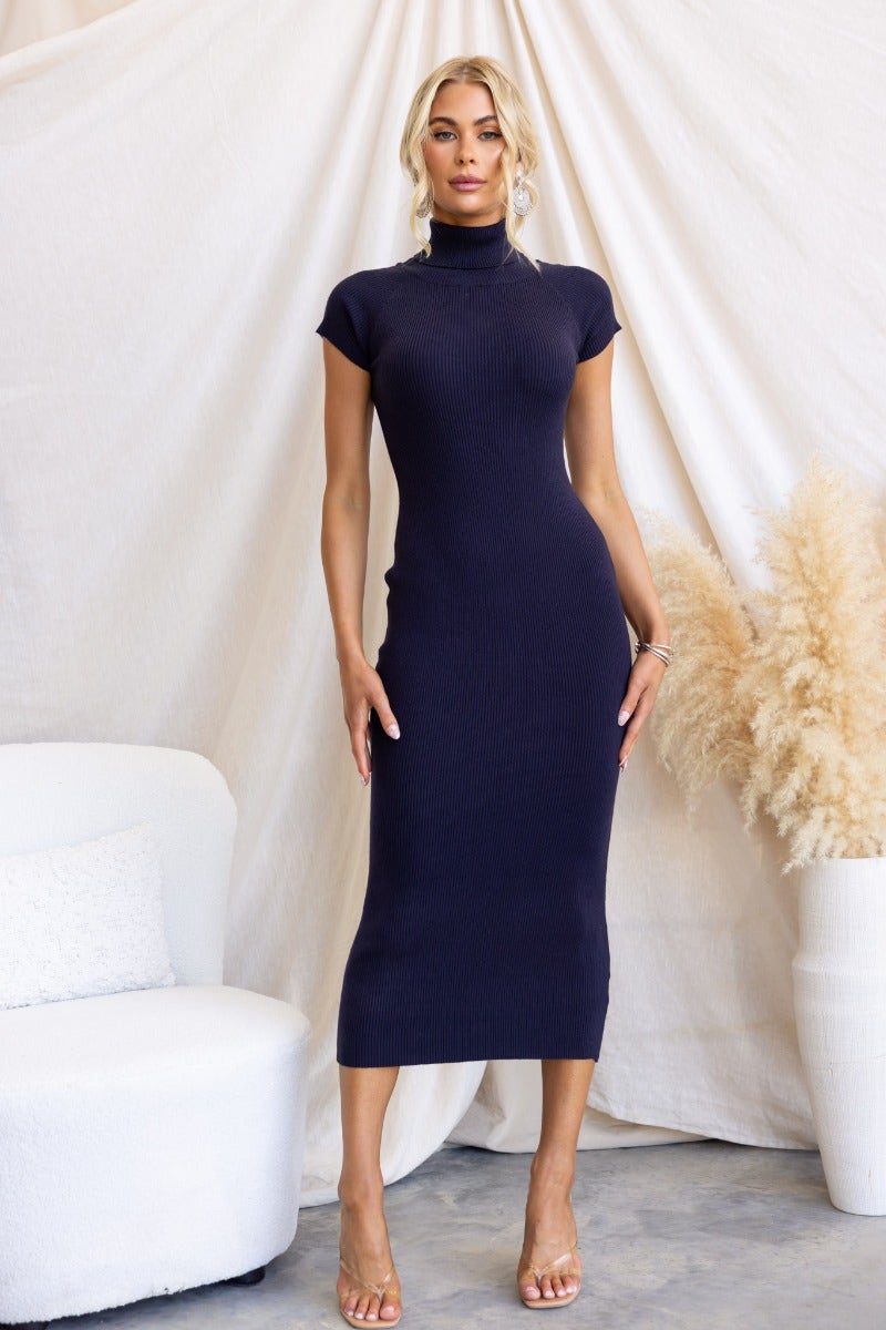 Navy ribbed knit midi dress on model, featuring a turtle neckline and fitted silhouette.