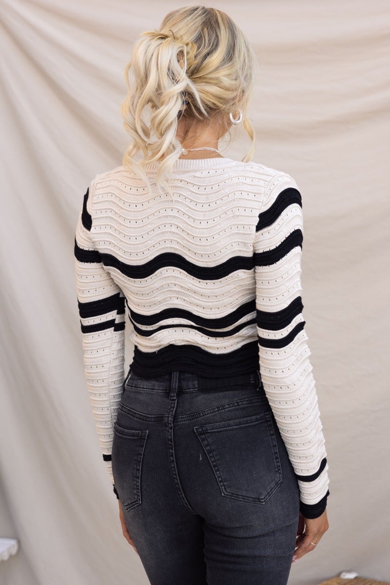 Back view of the Alanis Top, featuring a scoop neckline and semi open weave design, styled with black jeans.