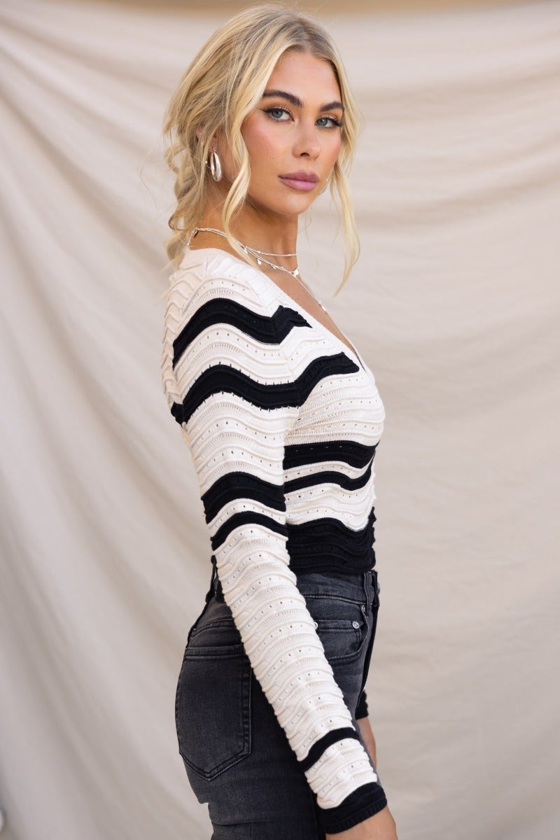 Alanis Top with scoop neckline in black and white, styled with high-waisted jeans, showcasing semi open weave design.