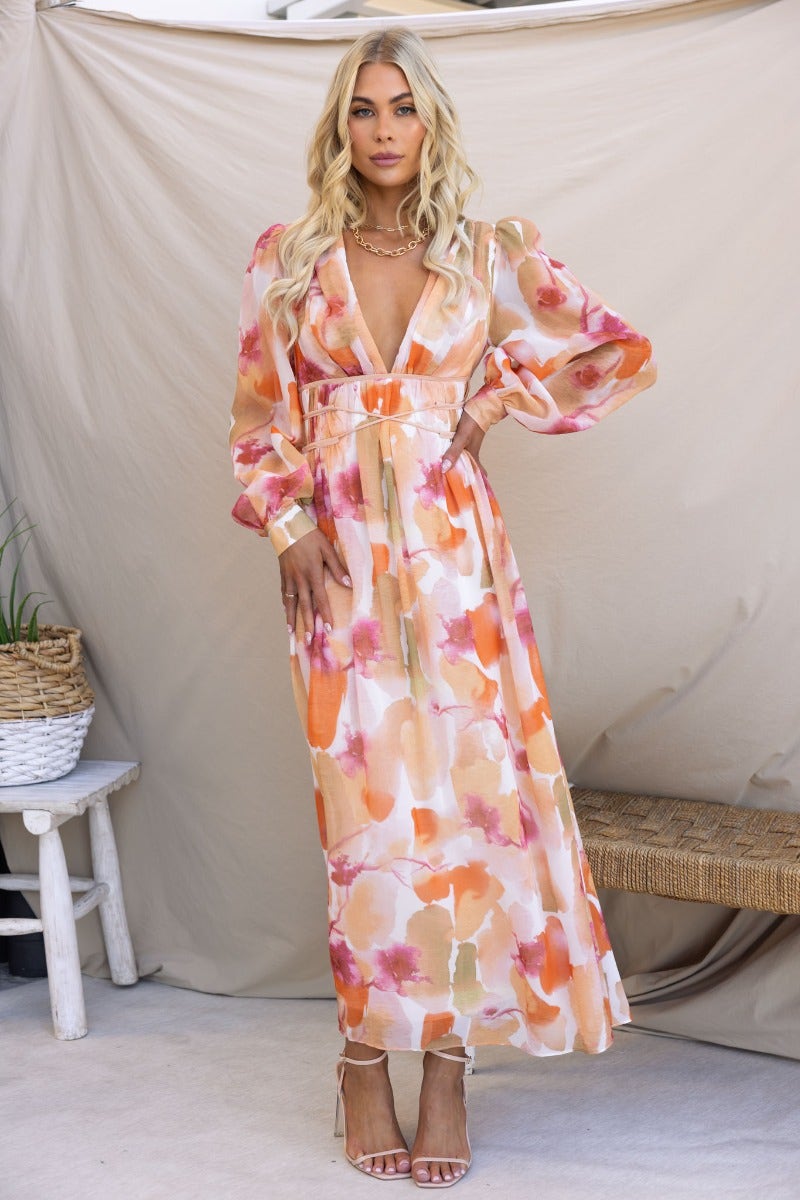 Model wearing a multi-colour maxi dress with V-neckline and long puff sleeves against a neutral background.