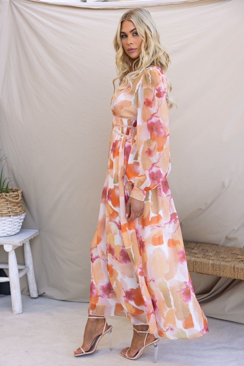 Model wearing a multi-colour maxi dress with V-neckline and elastic waistband, styled with strappy heels.