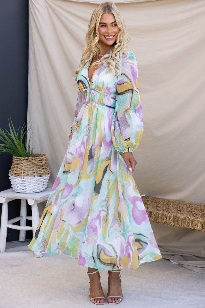 Haelyn Maxi Dress featuring a multi-colour print, V-neckline, and elastic cuffs, styled on a model indoors.