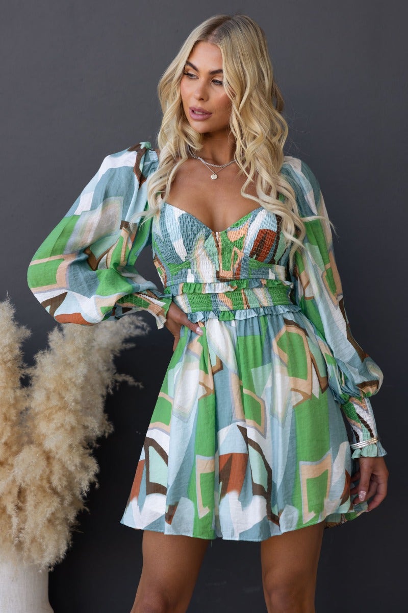 Model wearing a vibrant multi-colour pistachio dress with elastic bodice and puff sleeves, styled in a chic, modern setting.