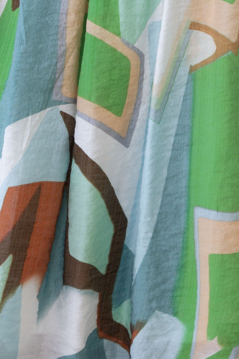 Close-up of a pistachio dress featuring multi-colour abstract print design on lightweight fabric.