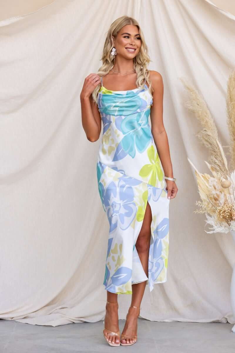 Model in a floral print Brighton midi dress with adjustable straps and front split on a neutral backdrop.