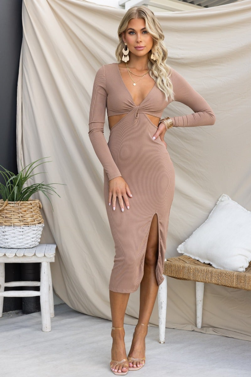 Model wearing a ribbed Fernanda Midi Dress in taupe with V-neckline and front split. Perfect for stylish occasions.