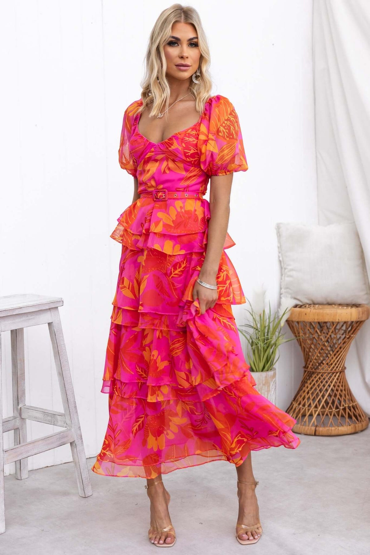Favourable maxi dress in vibrant pink and orange floral print, featuring ruffles, elastic sleeves, and a removable belt.