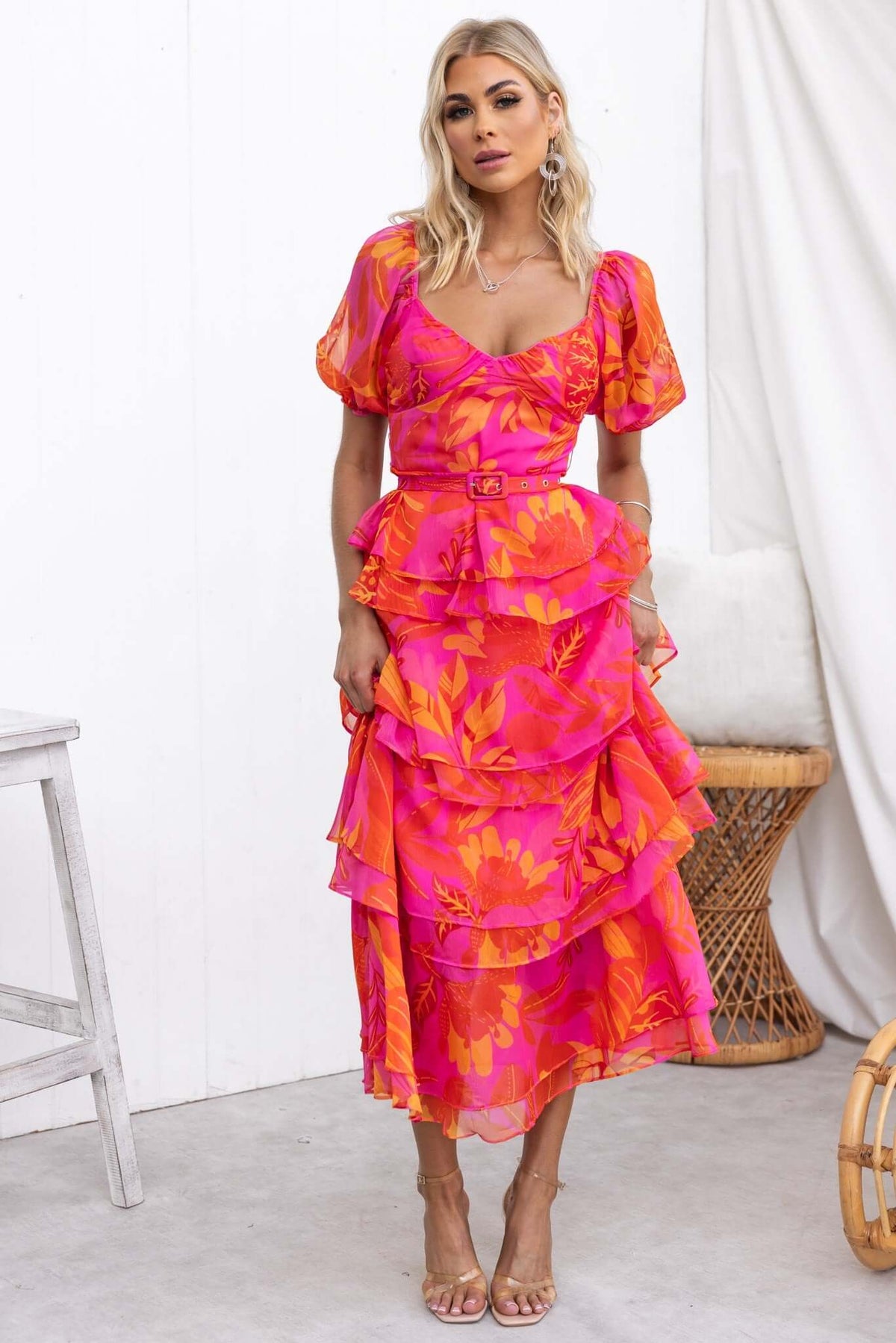 Favourable maxi dress in vibrant pink with floral pattern, featuring ruffles, elastic sleeves, and a removable belt.
