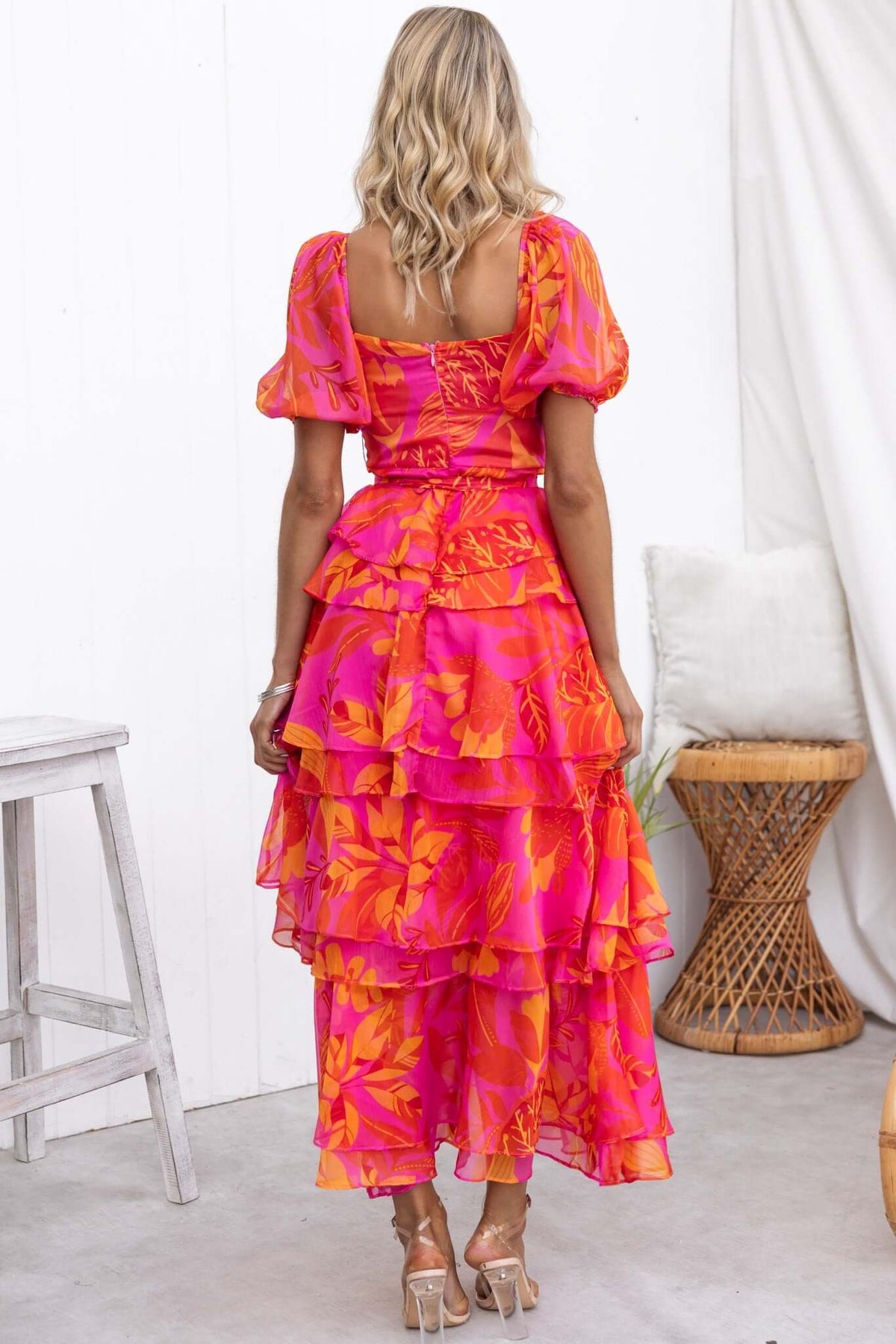 Back view of a Favourable Maxi Dress in vibrant pink with ruffle skirt and puff sleeves, styled with a removable belt.