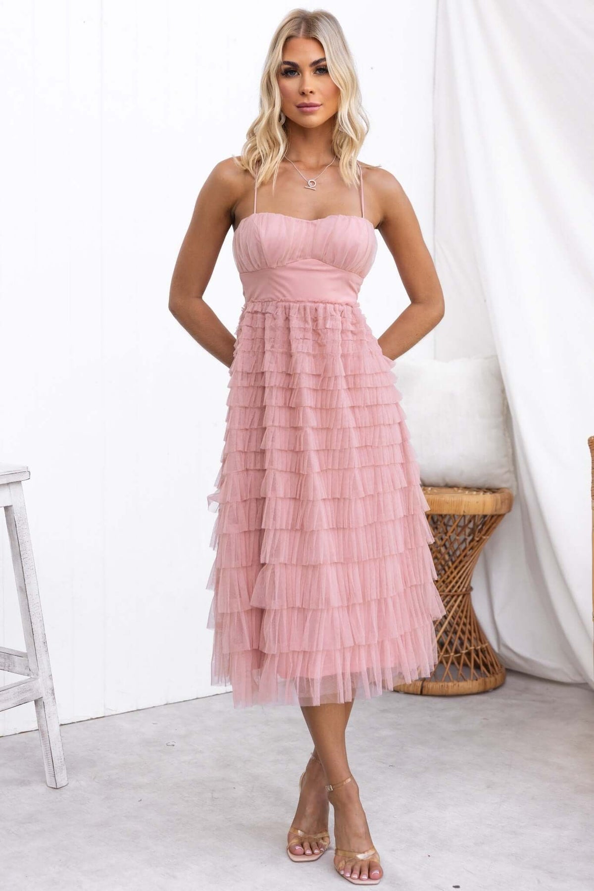 Model wearing the Vittoria Midi Dress, a pink tulle dress with adjustable straps and a tiered design.