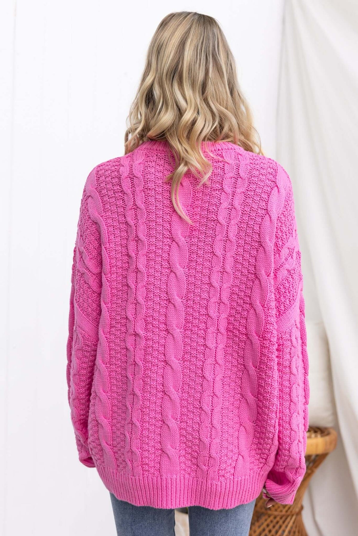 Back view of Varese Jumper in bright pink, featuring a round neckline and textured cable knit design.