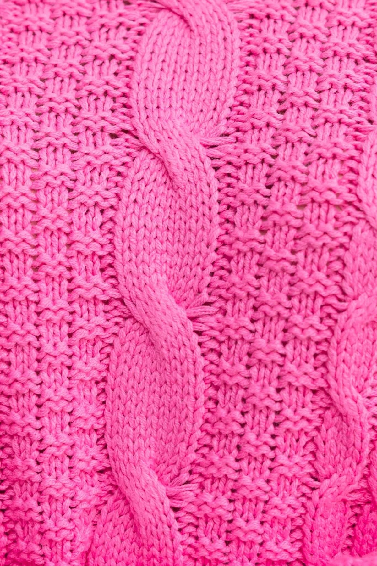Close-up of a vibrant pink cable knit fabric, showcasing intricate patterns and texture, perfect for a stylish jumper.