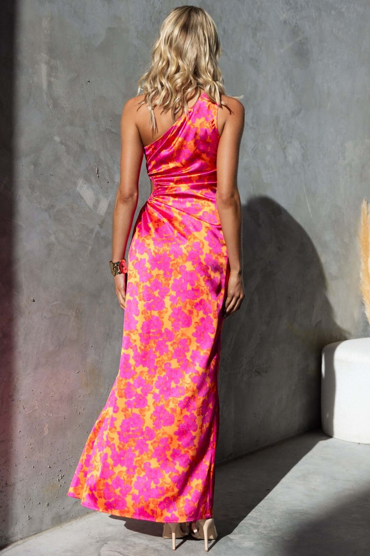 Model showcasing back of Carey Maxi Dress with floral print, one-shoulder neckline, and high front split.