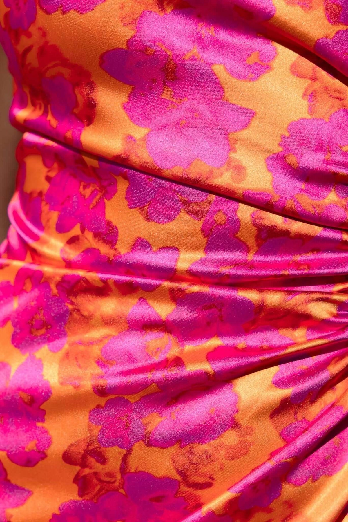 Close-up of Carey Maxi Dress featuring vibrant floral print in pink and orange satin fabric.