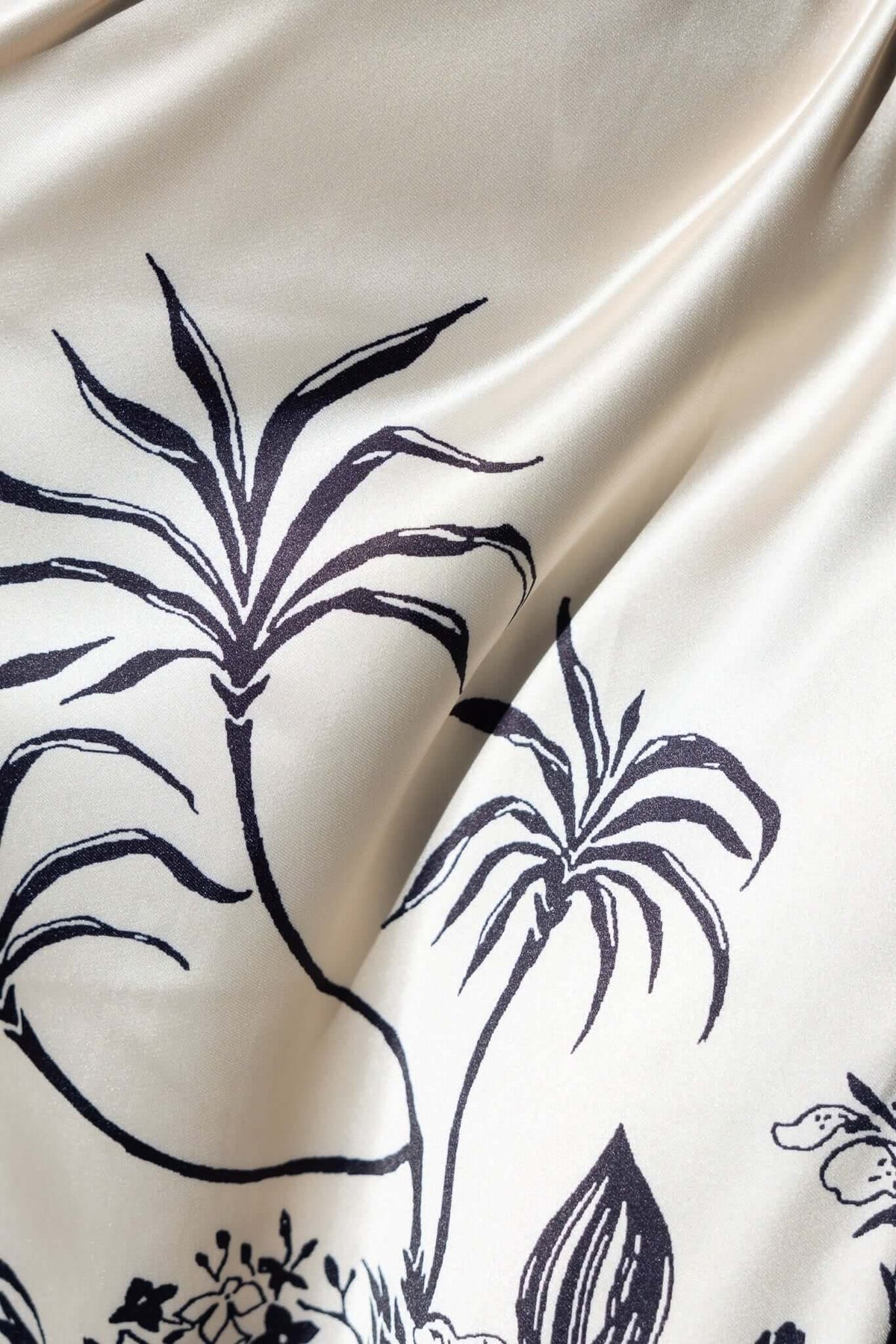 Close-up of floral print detail on satin fabric of Carey Maxi Dress, featuring botanical illustrations on a light background.