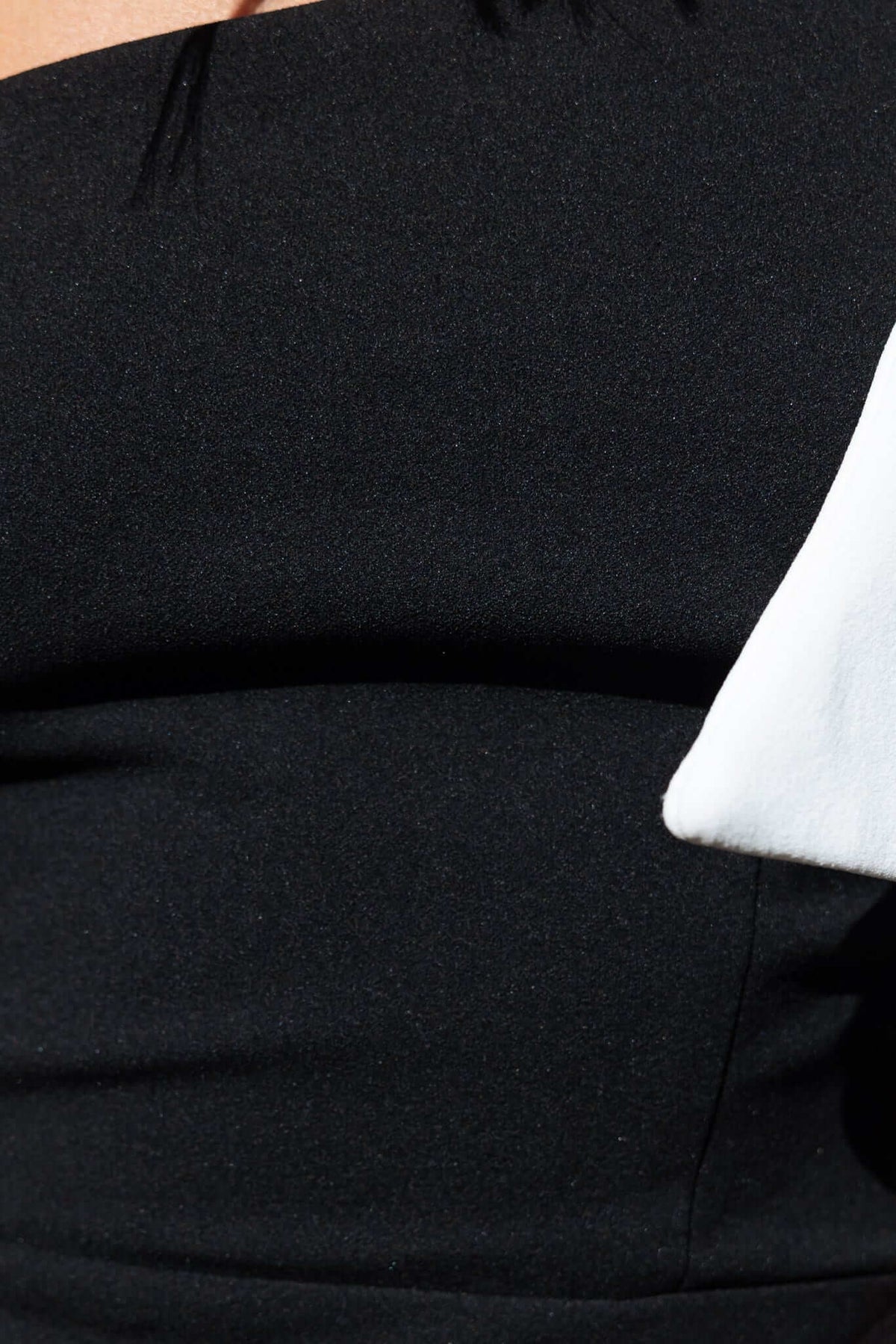 Close-up of black one-shoulder lany maxi dress featuring a bow overlay and textured fabric.