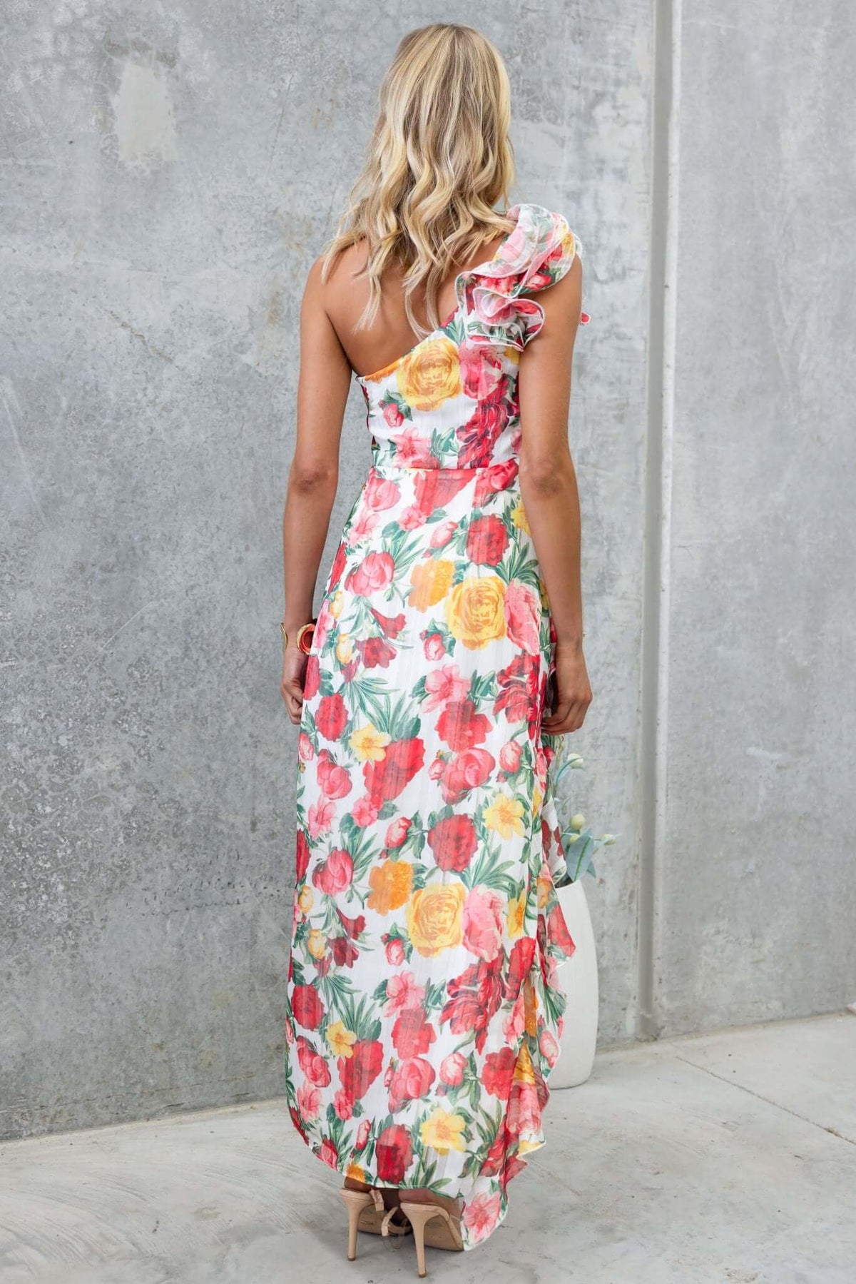 Back view of the Tresia Maxi Dress featuring floral print, one-shoulder design, and flowing silhouette.