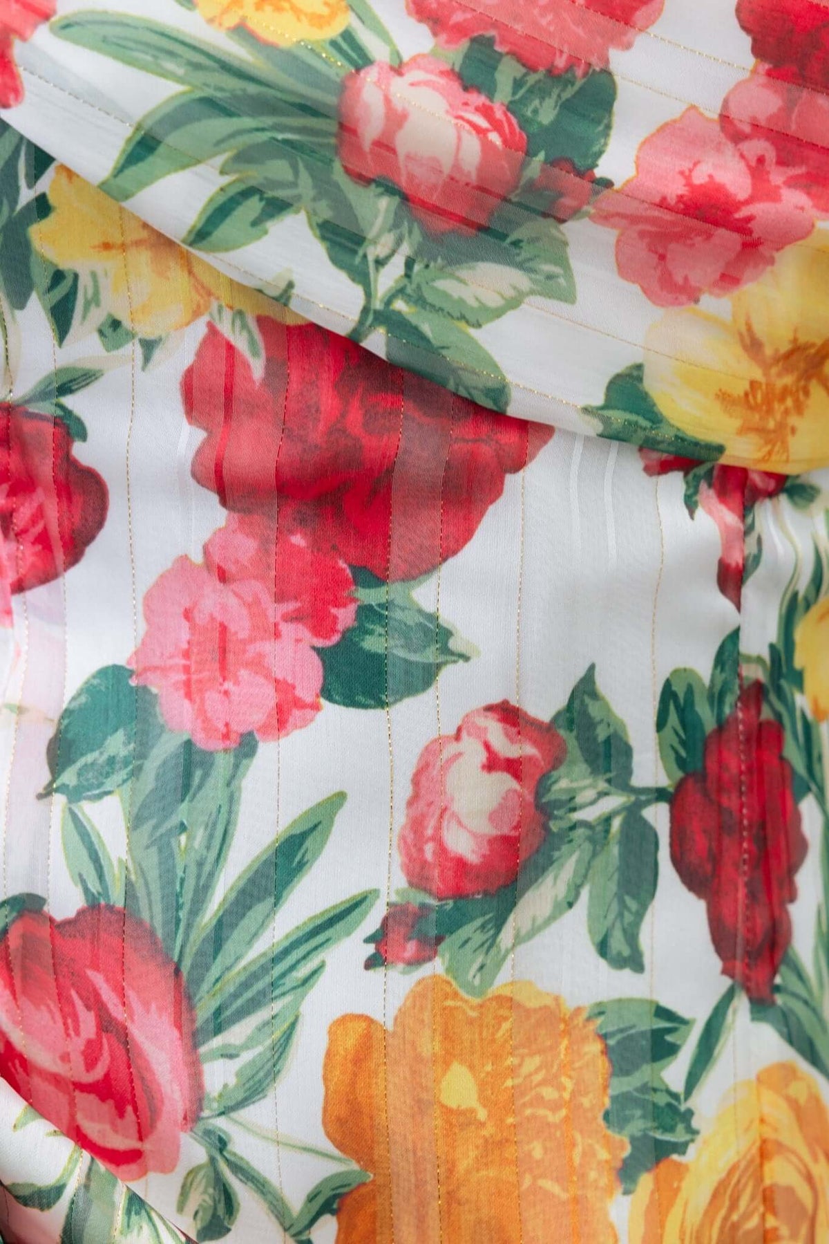 Close-up of floral fabric featuring red, pink, and yellow flowers, highlighting the delicate design of the Tresia Maxi Dress.