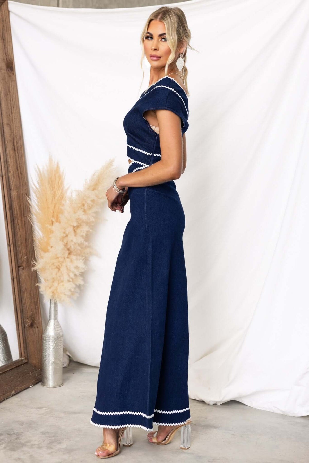 Side view of a woman wearing a Favara denim maxi dress featuring one-shoulder design and cut-out at waist.