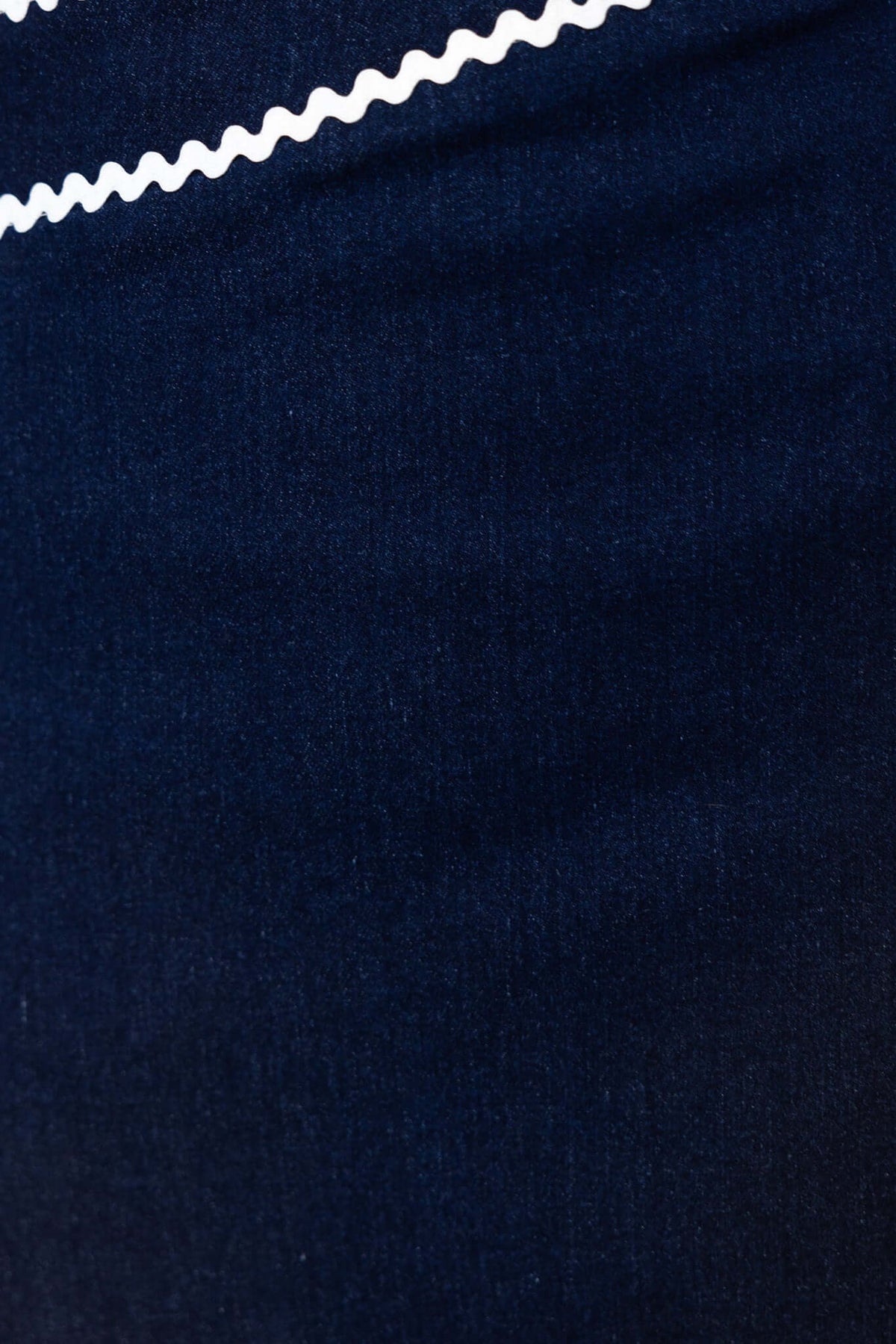 Close-up of navy denim fabric showcasing the texture and a decorative white zigzag trim design.