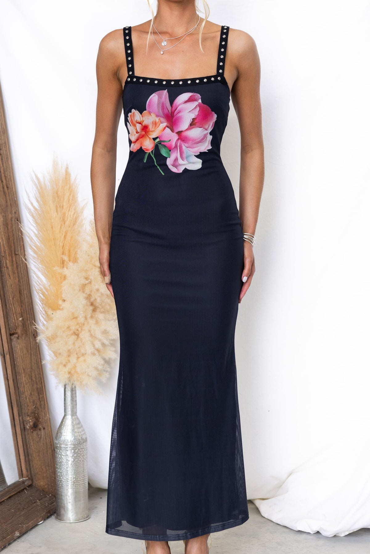 Model wearing Palermo Maxi Dress, a black dress with floral design, adjustable straps, and elegant fit.
