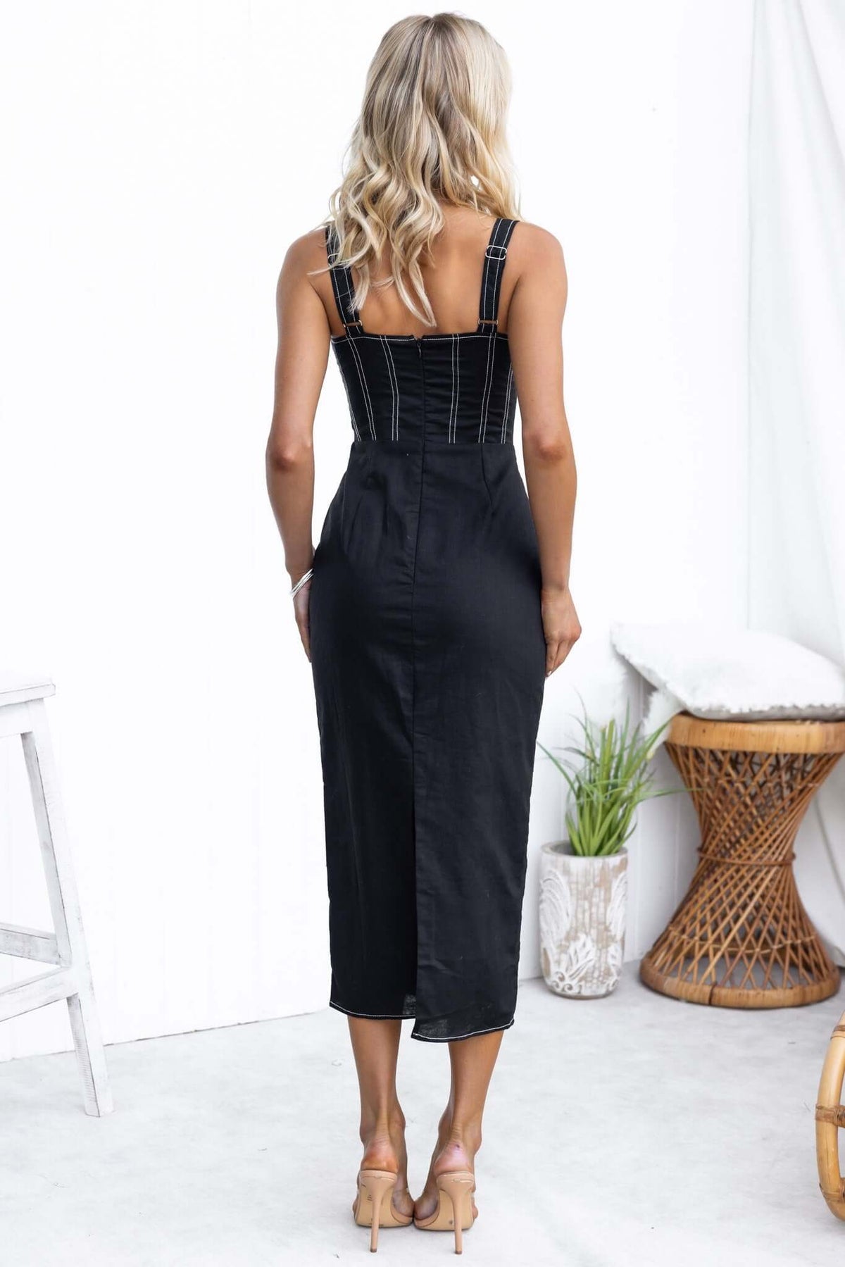 Back view of black Sebille Midi Dress with adjustable straps and split detail, styled with neutral accessories.