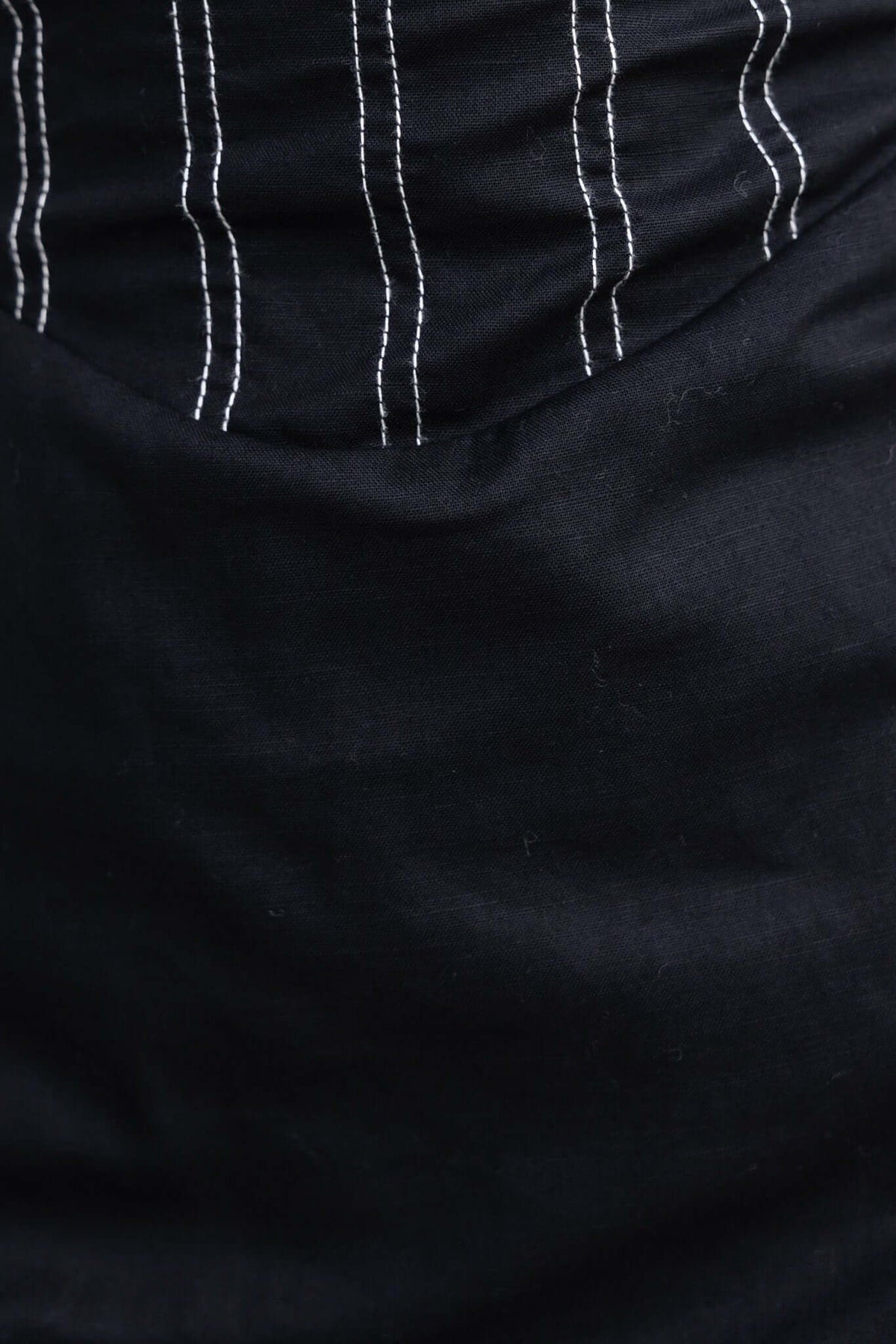 Close-up of a black fabric showing white striped pattern and smooth texture, ideal for a stylish midi dress.