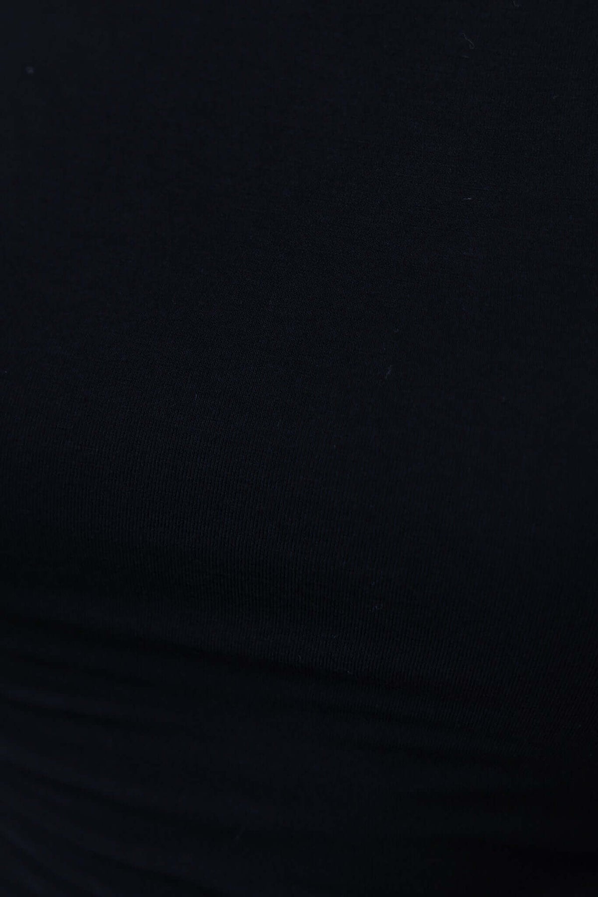 Close-up view of a black cotton blend top featuring a smooth, stretchy texture and ruched detailing.