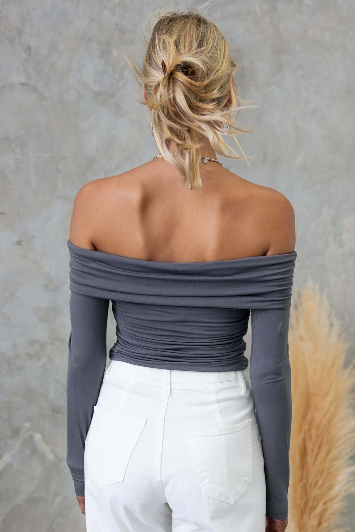 Back view of Harrie Top featuring off-shoulder neckline and ruched design, paired with white jeans.