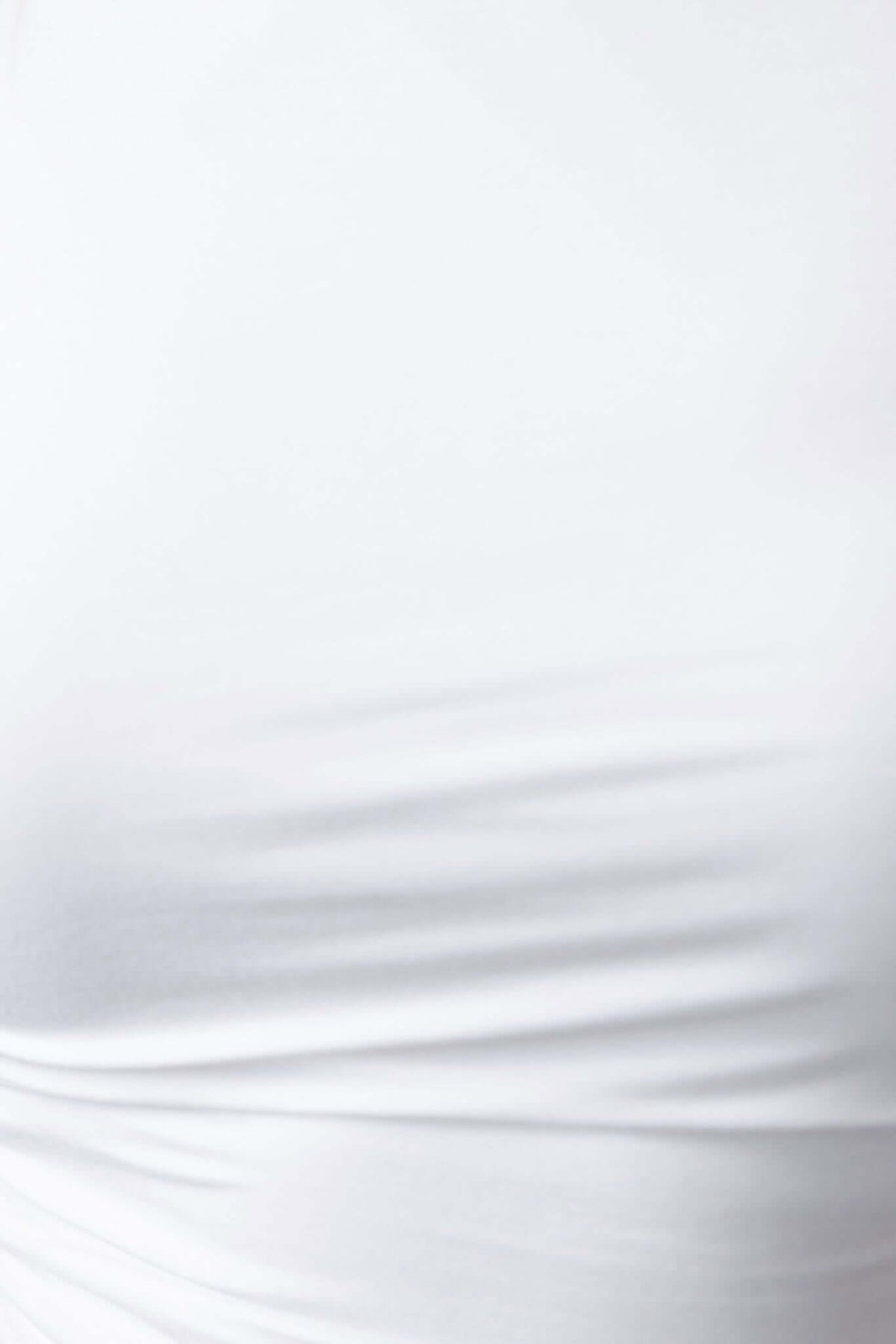 Close-up of white cotton blend top with ruched sides and boat neckline, showcasing its soft stretch fabric.