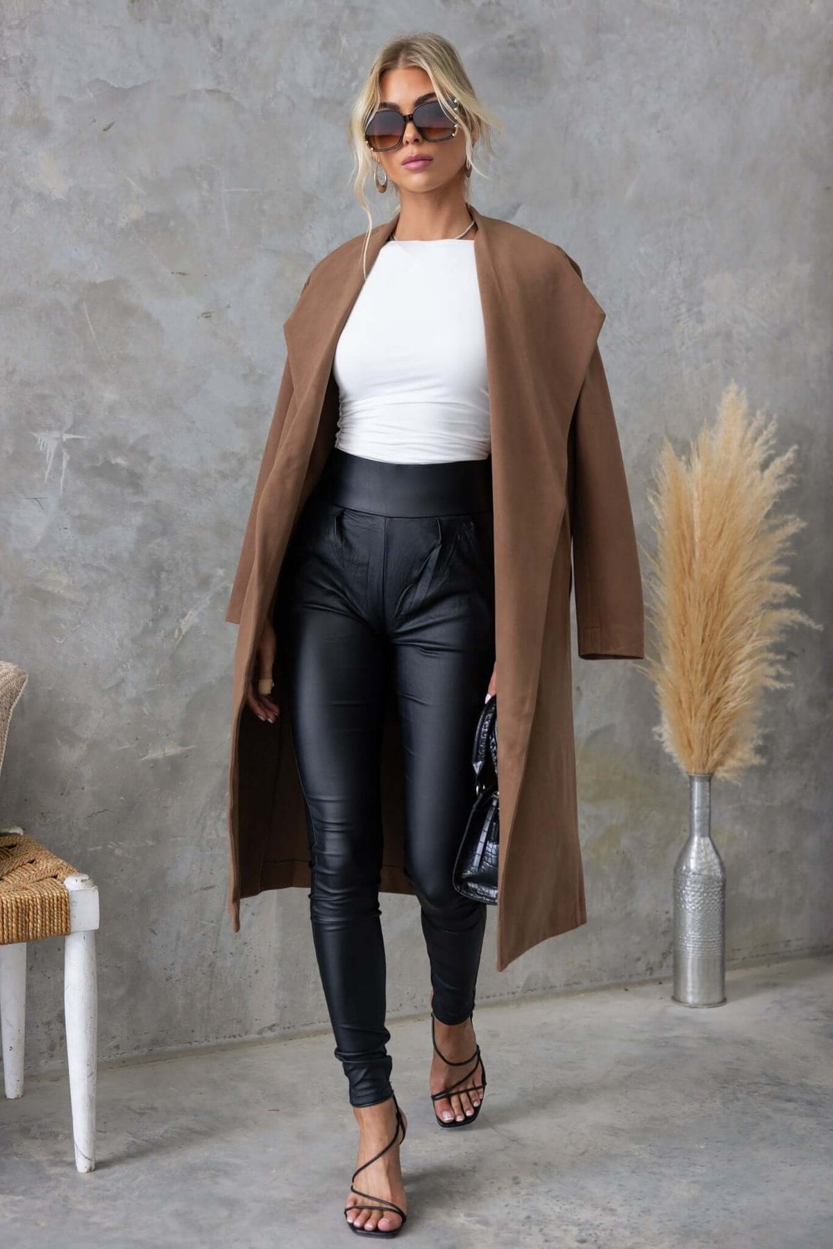 Model wearing the Aria Coat, a longline suede-style coat, styled with a white top and black leather pants.