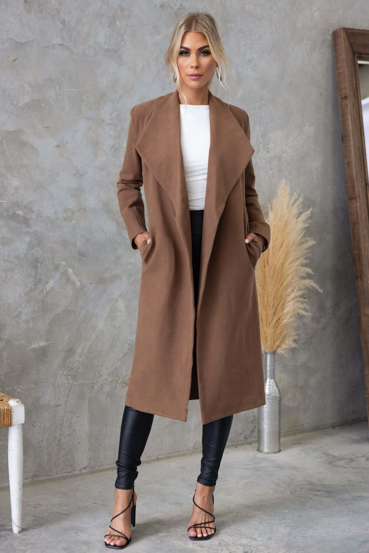 Aria Coat in brown with collar and lapel, styled with black pants and heels, perfect for a chic look.